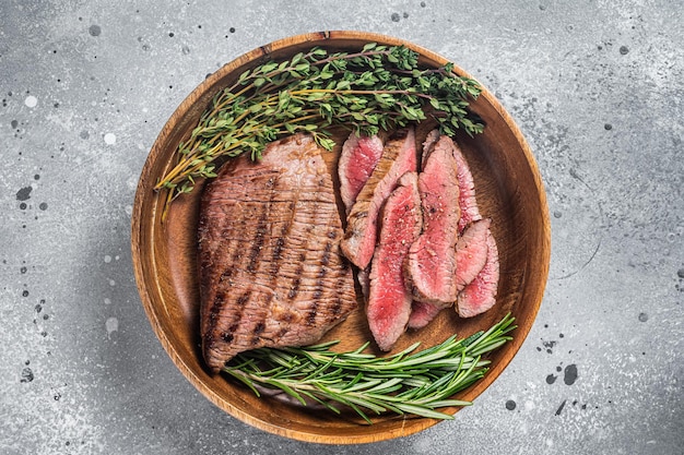 Bistecca di gonna affettata alla griglia su un piatto con erbe Sfondo grigio Vista dall'alto