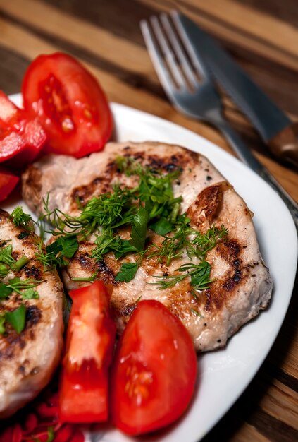 Bistecca di maiale con pomodori ed erbe fresche.