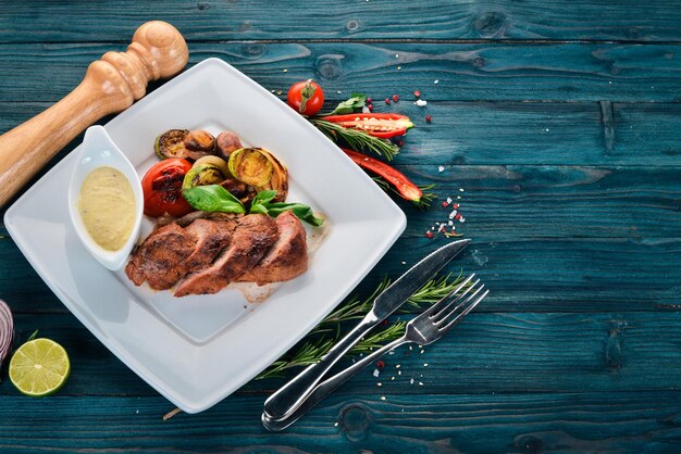 Bistecca di maiale con verdure grigliate su un piatto su uno sfondo di legno Vista dall'alto Copia spazio