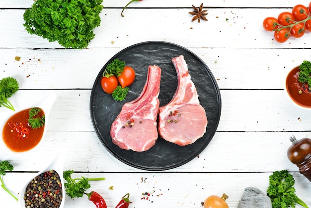 Bistecca di maiale cruda con l'osso Su un piatto di spezie ed erbe aromatiche Vista dall'alto Spazio libero per il testo