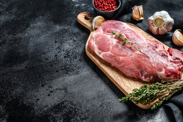 Bistecca di maiale in marmo crudo su un tagliere di legno