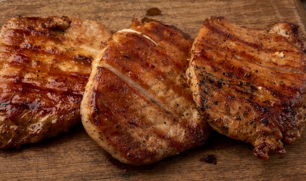 Bistecca di maiale succosa fritta su una tavola di legno, carne alla griglia