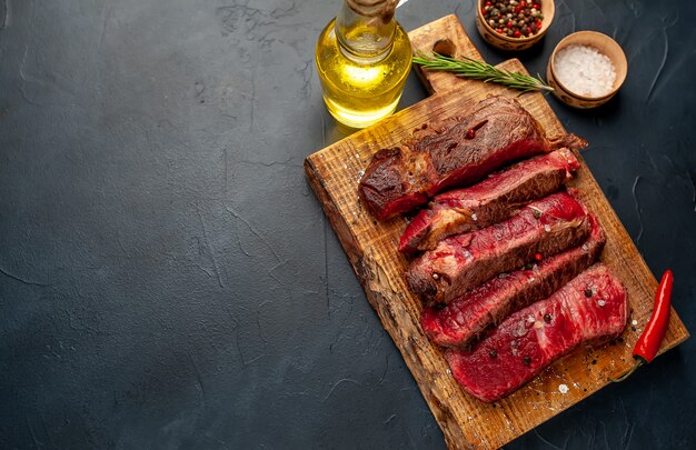 Bistecca di manzo alla griglia con erbe e spezie su uno sfondo di pietra con copia spazio per il testo