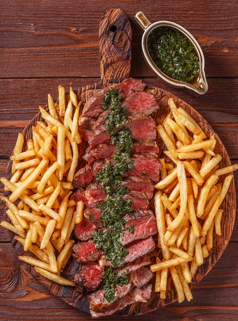 Bistecca di manzo alla griglia con salsa chimichurri e patatine fritte.