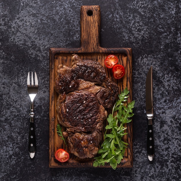 Bistecca di manzo alla griglia con spezie su una tavola di legno, vista dall'alto.