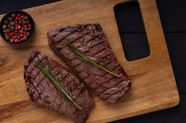 Bistecca di manzo alla griglia due con spezie e rosmarino sul tagliere