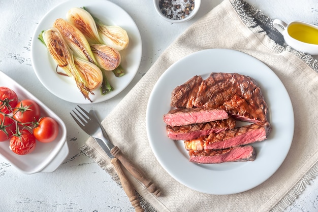 Bistecca di manzo alla griglia guarnita con lattuga fresca, cipolle e pomodorini