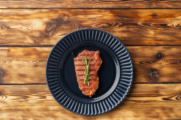 Bistecca di manzo alla griglia servita sul piatto blu sul tavolo