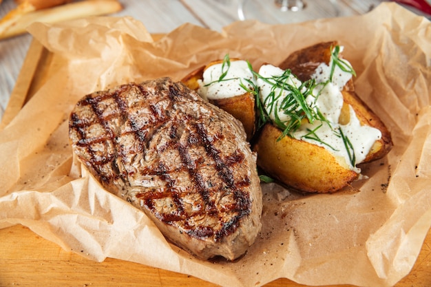 Bistecca di manzo con patate al forno con panna acida