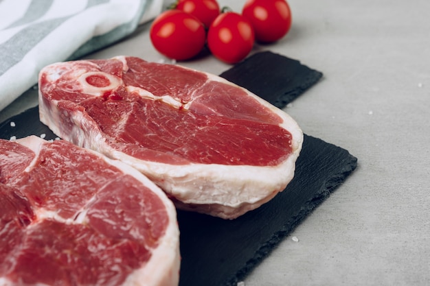 Bistecca di manzo cruda rib-eye sul tagliere di legno su gray