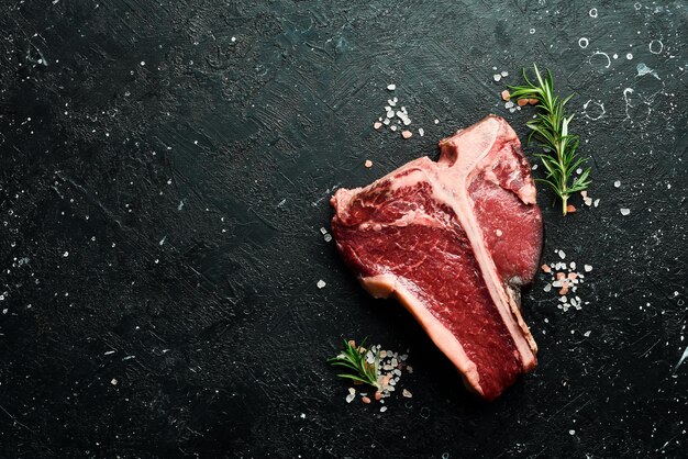 Bistecca di manzo cruda stagionata a secco o porterhouse su sfondo di pietra nera Vista dall'alto