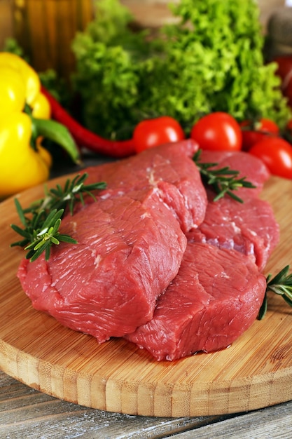 Bistecca di manzo cruda sul tagliere con verdure e verdure su fondo di legno