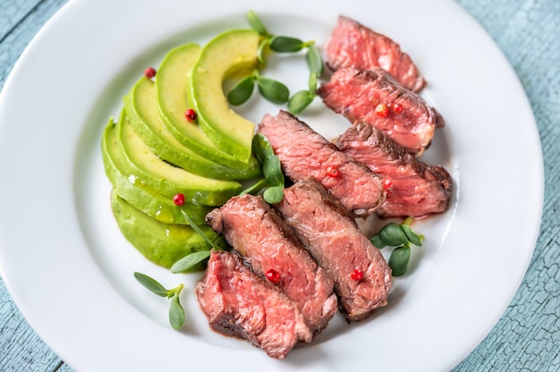 Bistecca di manzo decorata con pepe rosso e guarnita con fette di avocado