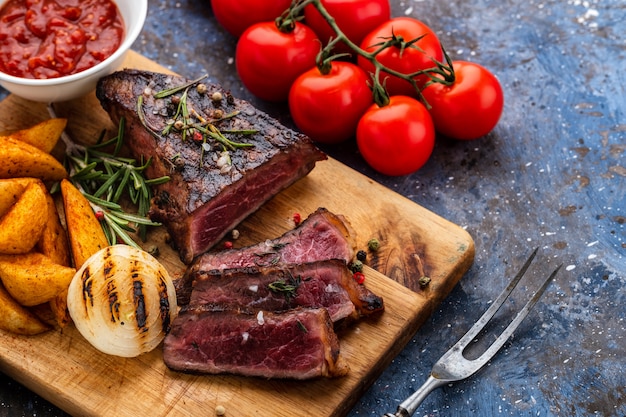 Bistecca di manzo deliziosa sul tagliere di legno. Barbecue di manzo alla griglia a fette con pomodorini