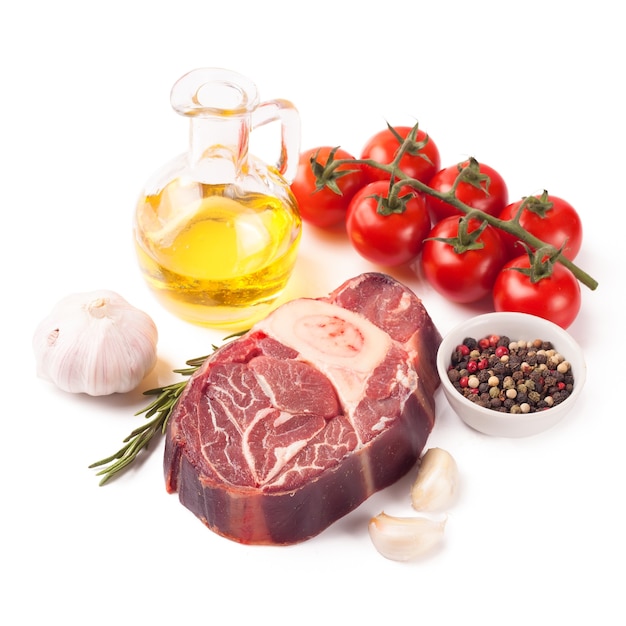 Bistecca di manzo di carne cruda con osso, spezie, rosmarino e ingredienti da cucina isolati su priorità bassa bianca.