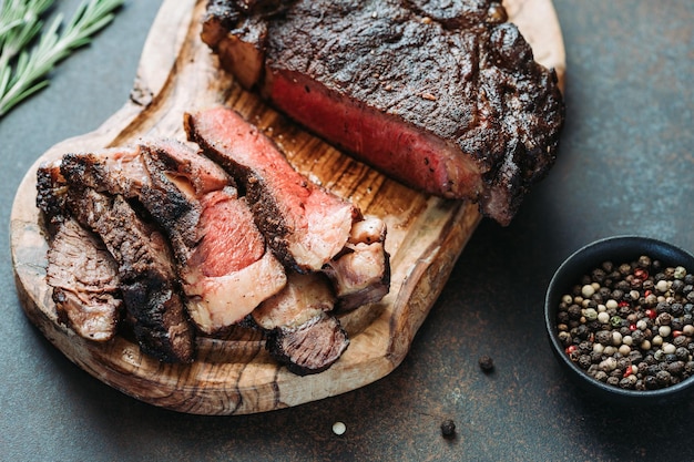 Bistecca di manzo in marmo essiccato Tomahawk su tavola di legno con spezie Concetto di cena in primo piano