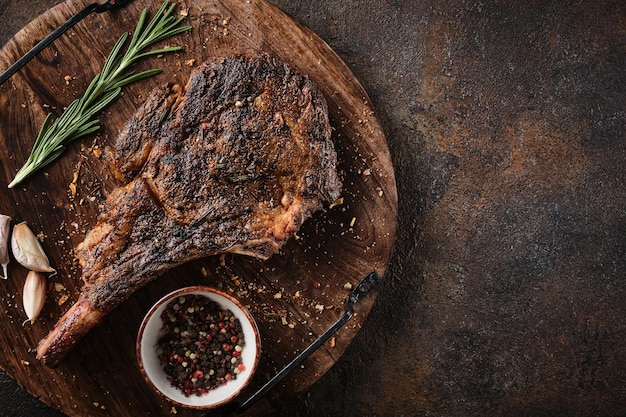 Bistecca di manzo in marmo essiccato Tomahawk su tavola di legno con spezie Concetto di cena piatta