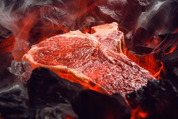 Bistecca di manzo marmorizzata cruda con carbone e fumo