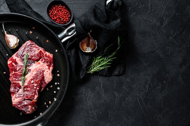 Bistecca di manzo marmorizzata in padella. Carne di fattoria biologica. Sfondo nero. Spazio per il testo