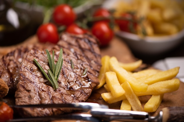 Bistecca di manzo mediamente rara alla griglia affettata servita con patatine fritte da vicino