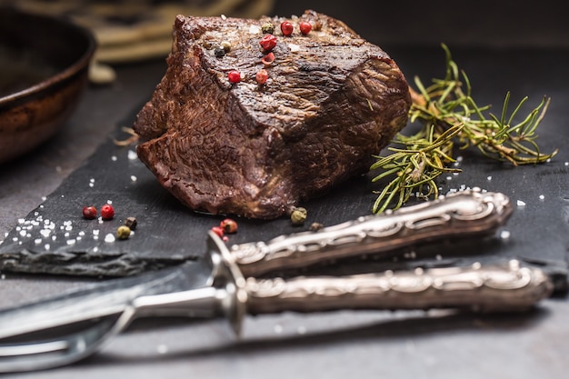 Bistecca di manzo succosa con spezie ed erbe aromatiche sul tagliere.