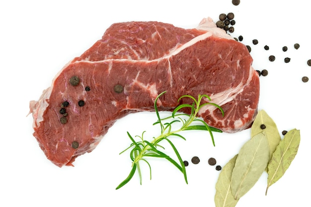 Bistecca di manzo vista di manzo fresco su sfondo bianco con foglie di rosmarino pepe nero