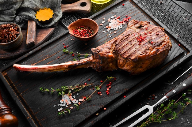 Bistecca di osso Bistecca di Tomahawk su fondo di legno nero Vista dall'alto Spazio libero per il testo