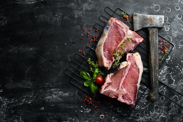 Bistecca di osso crudo con un'ascia Vista dall'alto su uno sfondo di pietra nera