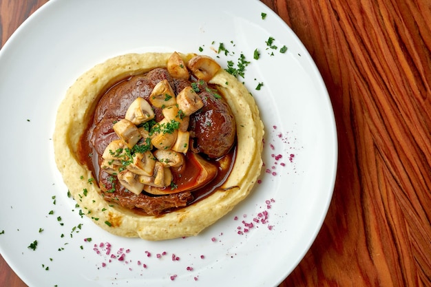 Bistecca di ossobuco con salsa di funghi e purè di patate su un tavolo di legno