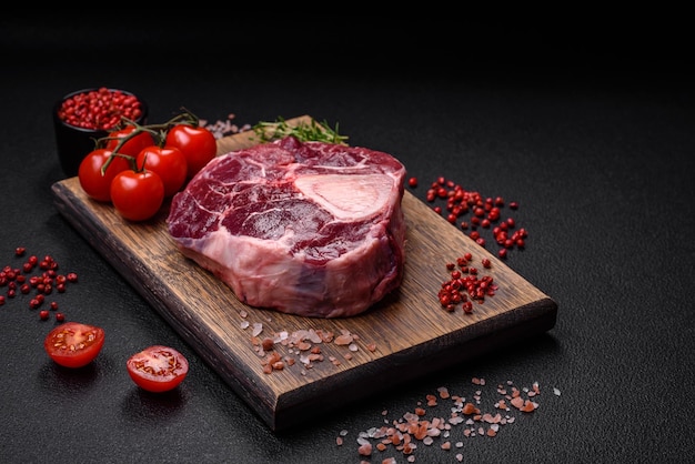 Bistecca di ossobuco di manzo fresco con spezie ed erbe aromatiche su fondo in cemento strutturato