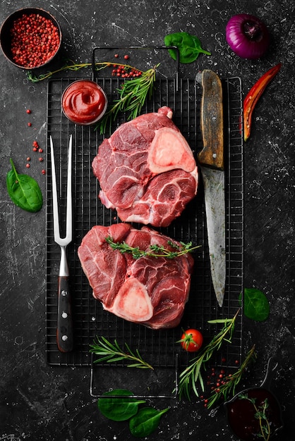 Bistecca di ossobuko di carne fresca con osso con rosmarino e spezie su sfondo di pietra nera Vista dall'alto