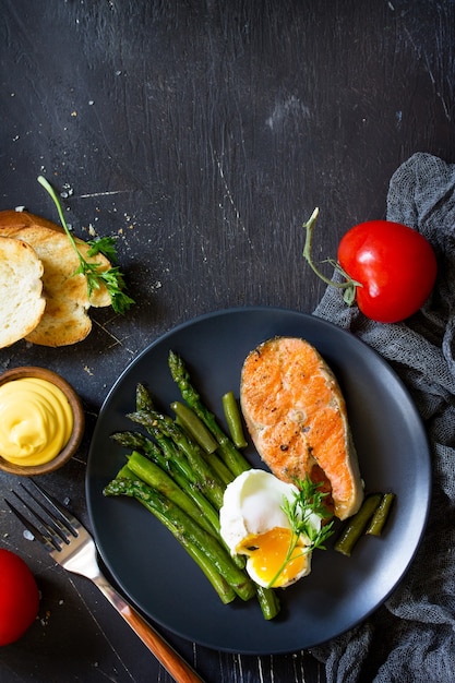 Bistecca di pesce di salmone alla griglia con uovo in camicia di asparagi Vista dall'alto piatta Spazio libero per il testo