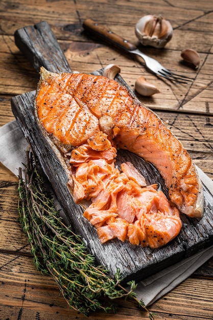 Bistecca di pesce trota salmone alla griglia su una tavola di legno con erbe aromatiche. Fondo in legno. Vista dall'alto.