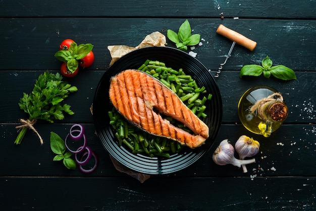 Bistecca di salmone al forno con fagiolini su un piatto nero Vista dall'alto Spazio di copia gratuito