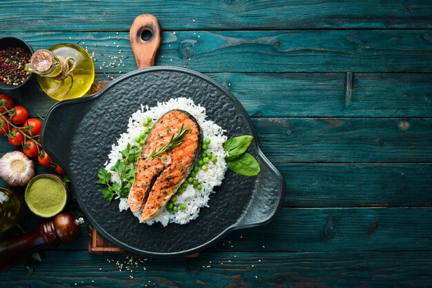 Bistecca di salmone al forno con riso e verdure su una lastra di pietra nera Frutti di mare Vista dall'alto Spazio libero per il testo