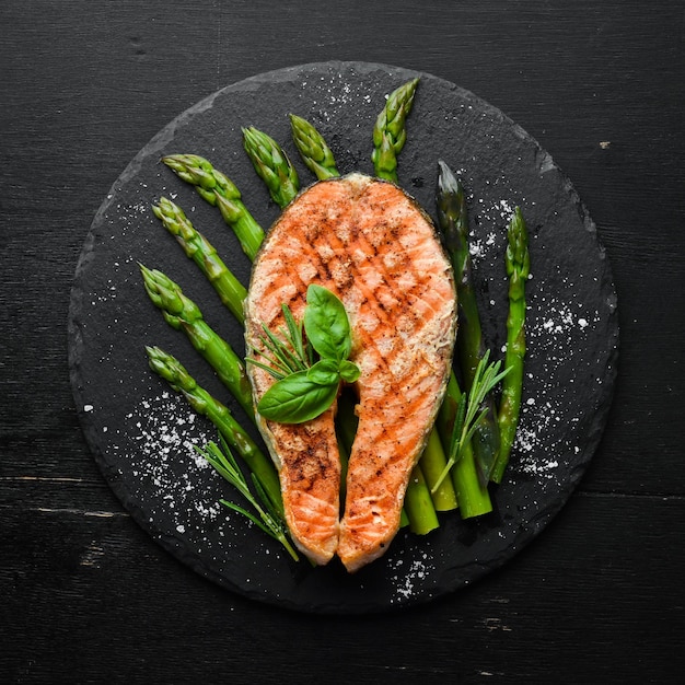 Bistecca di salmone con asparagi al forno e spezie su una lastra di pietra nera Vista dall'alto Spazio libero per il testo