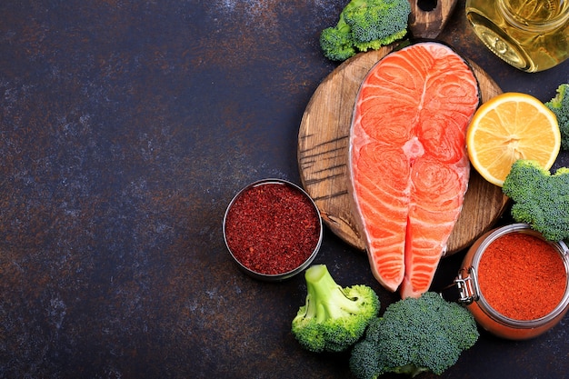 Bistecca di salmone crudo con limone e olio d'oliva su uno sfondo scuro Vista dall'alto.