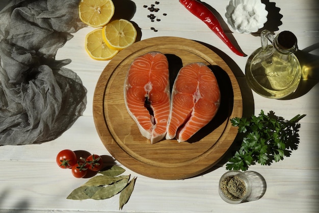 Bistecca di salmone fresco con ingredienti su fondo di legno bianco