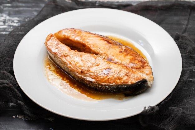 bistecca di salmone fritta con salsa su un piccolo piatto bianco