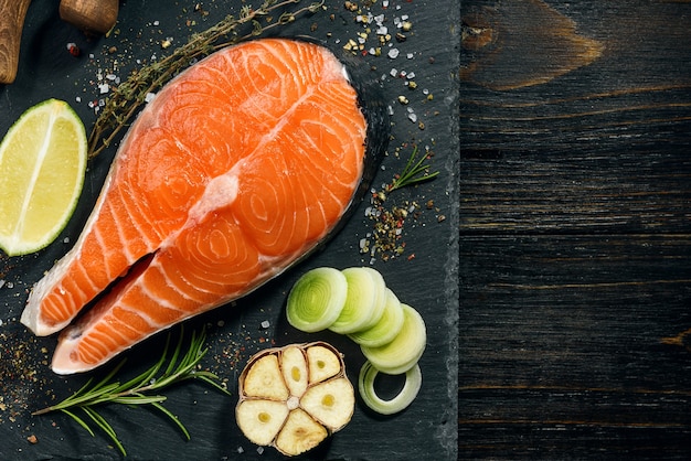 Bistecca di salmone preparata per la frittura con ingredienti su sfondo scuro