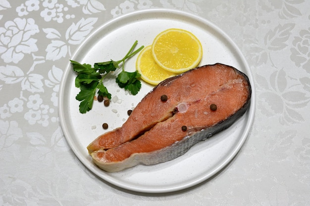 bistecca di salmone rosa isolato su piatto bianco con fette di limone, primo piano