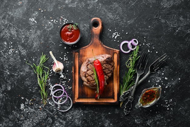 Bistecca di vitello alla griglia con spezie su sfondo di pietra nera Vista dall'alto Spazio per la copia gratuito