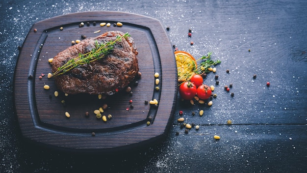 Bistecca di vitello con spezie sul tagliere. Vista dall'alto. Spazio libero per il testo. Su uno sfondo di legno.