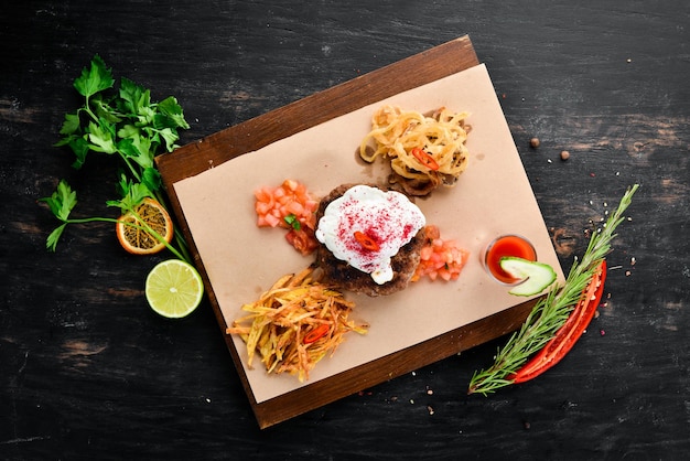 Bistecca di vitello con uovo in camicia e succo di pomodoro Su uno sfondo di legno Vista dall'alto Spazio libero per il testo