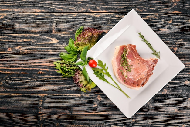 Bistecca di vitello cruda su un piatto su uno sfondo di legno Vista dall'alto Spazio libero per il testo