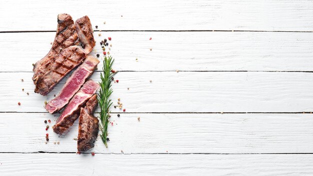 Bistecca di vitello su un osso su uno sfondo di legno bianco Spazio libero per il testo Vista dall'alto