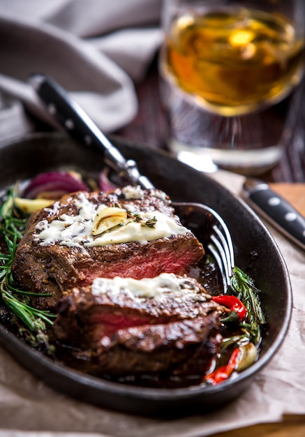 Bistecca e verdure mediamente cotte alla griglia magra salutare con bicchiere di whisky e una spezia in un pub rustico o in una taverna