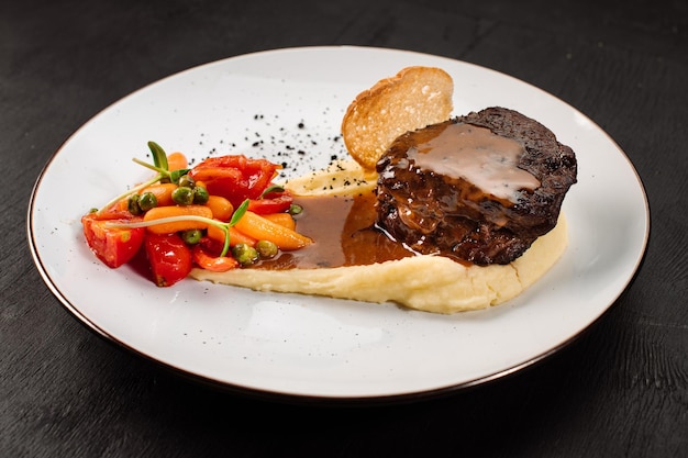 Bistecca fresca e gustosa con purè di patate e verdure bollite su fondo di legno