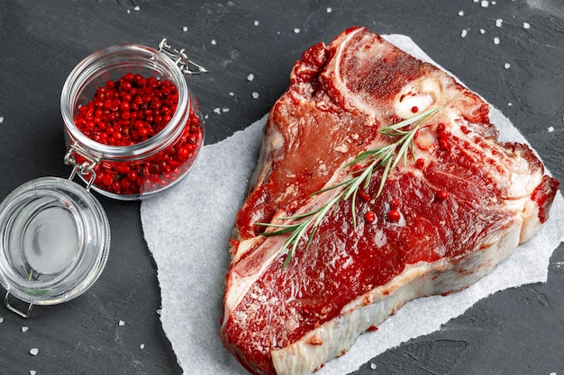 Bistecca nella lombata cruda della carne fresca con le spezie su un fondo scuro