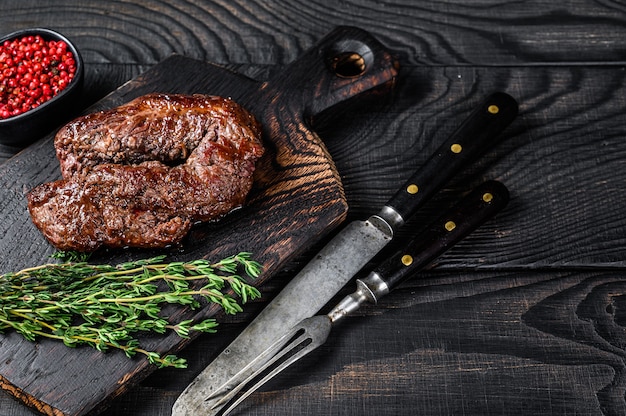 Bistecca tenera appesa alla griglia barbecue su un tagliere di legno